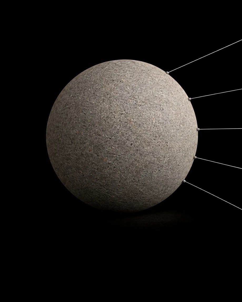 A stone sphere lit in full, held by taut wires running out of frame.